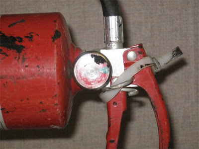 Fire extinguisher with an improper zip tie, securing the handle, making it difficult or impossible to remove during a fire event.